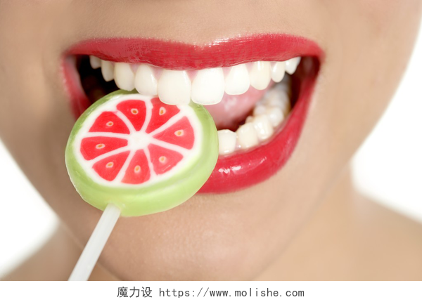 白色背景上一个女人吃棒棒糖在完美的女人的牙齿多彩棒棒糖